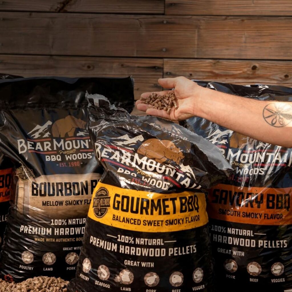Bear Mountain BBQ pellet bags with hardwood pellets in hand