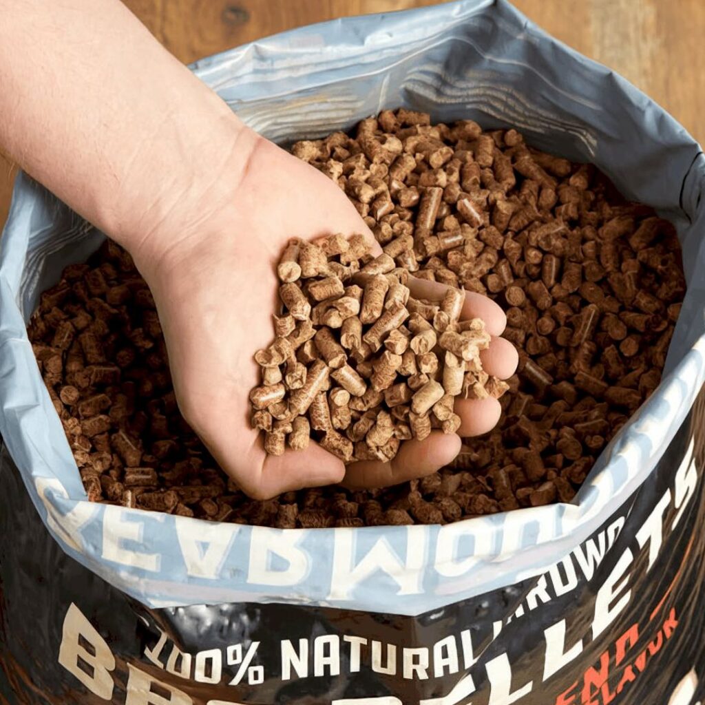 Hand holding Bear Mountain BBQ hardwood pellets from an open bag
